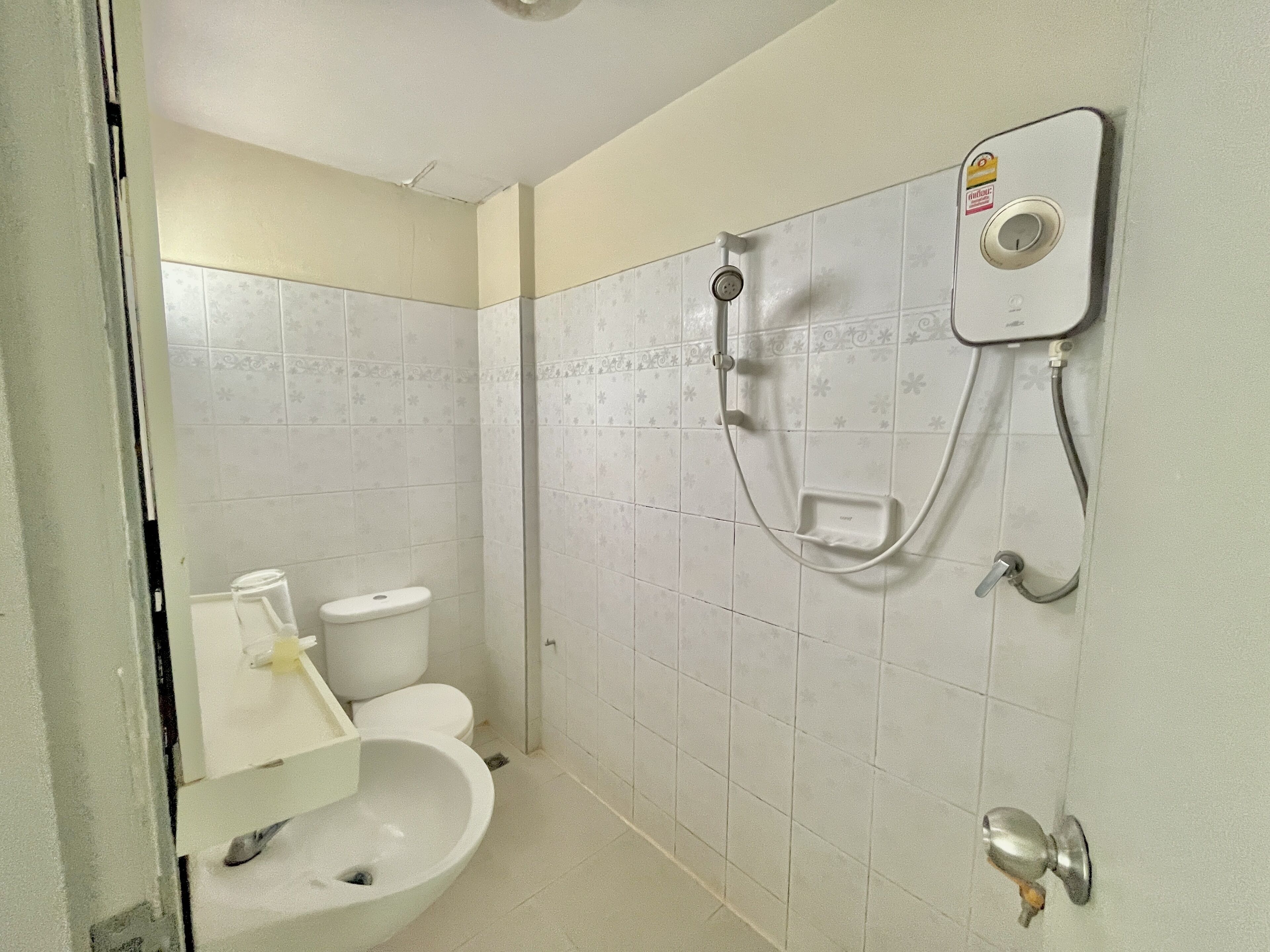 Un baño con inodoro, lavamanos y ducha con panel de control.
