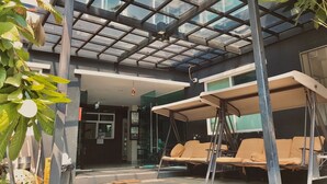 Un espace extérieur abrité, doté de sièges confortables et d’une verrière.