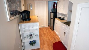 Una cocina compacta con armarios blancos, cafetera, microondas y refrigerador.