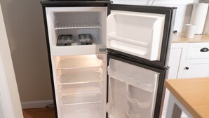 Un refrigerador compacto con dos puertas, un compartimento congelador y varios estantes.