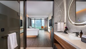 Ein modernes Hotelzimmer mit einem großen Bett, einem Badezimmer mit Spiegel und Waschbecken sowie Blick auf die Stadt.