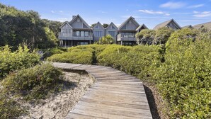 A wooden boardwalk leading to a row of houses with balconies, surrounded by dense greenery. - AMAZING Ocean Front View! Popular 3BR Seascape Condo! (Kiawah Island)