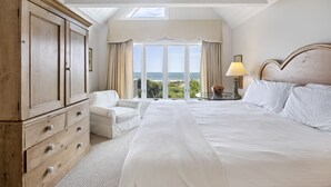 A bedroom with a large bed, a wardrobe, a chair, and a view of the sea. - AMAZING Ocean Front View! Popular 3BR Seascape Condo! (Kiawah Island)