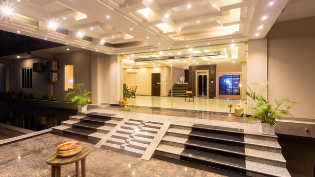Eine Hotelhalle mit Marmorboden, einer Treppe zum Obergeschoss und einer Rezeption mit Glastrennwand.