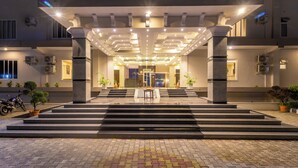 Ein Hotel mit moderner Gestaltung, das eine zentrale Treppe, eine Rezeption und eine gut beleuchtete Fassade zeigt.