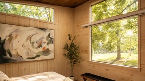 Un dormitorio con cama, una banca y un cuadro en la pared.