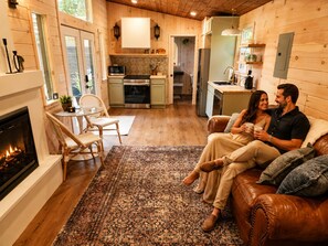 Una sala de estar acogedora con chimenea, un comedor con mesa y sillas, y una cocina al fondo.