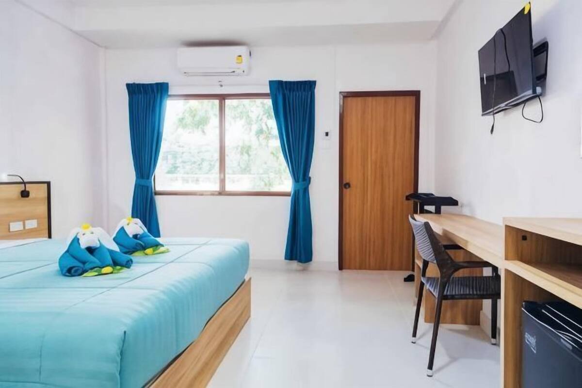A hotel room with a bed, a desk, a chair, a TV, and a wardrobe.