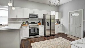 Une cuisine moderne avec des armoires blanches, des appareils en acier inoxydable et un plancher en bois.