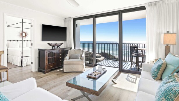 A spacious living room with a large glass door leading to a balcony with a view of the sea. - One Seagrove Place 0406 (Santa Rosa Beach)