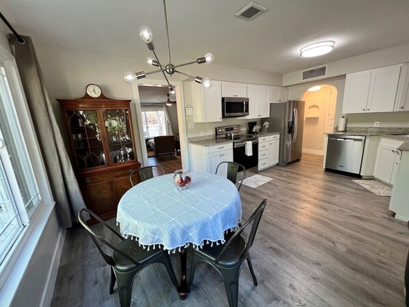 A modern kitchen with white cabinets, stainless steel appliances, and a dining area with a round table and chairs.
