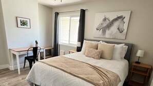 Un dormitorio con cama, escritorio, silla y ventana con cortinas.
