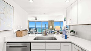 Une cuisine moderne avec des meubles blancs, un lave-vaisselle intégré et une vue sur le balcon.