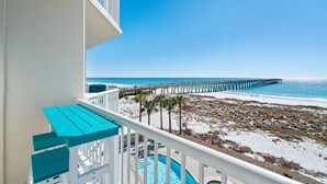 Ein Balkon mit Blick auf einen Strand, eine Pier und ein Schwimmbad.