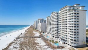 Ein Hotel direkt am Strand mit mehreren Etagen, einem Pool und Blick auf den Strand.