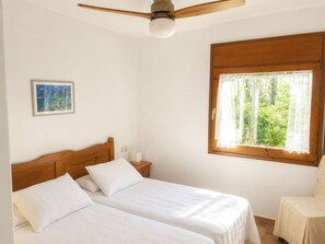 A bedroom with two beds, a ceiling fan, a window with lace curtains, and a framed picture on the wall. - "Melis II M6-Playa de Pals" by Interhome (Pals)