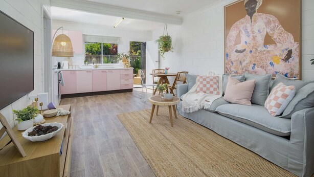 A modern living room with a grey sofa, a coffee table, and a kitchen in the background. - Palm Springs Oasis, short walk to Shelly Beach (Bateau Bay)
