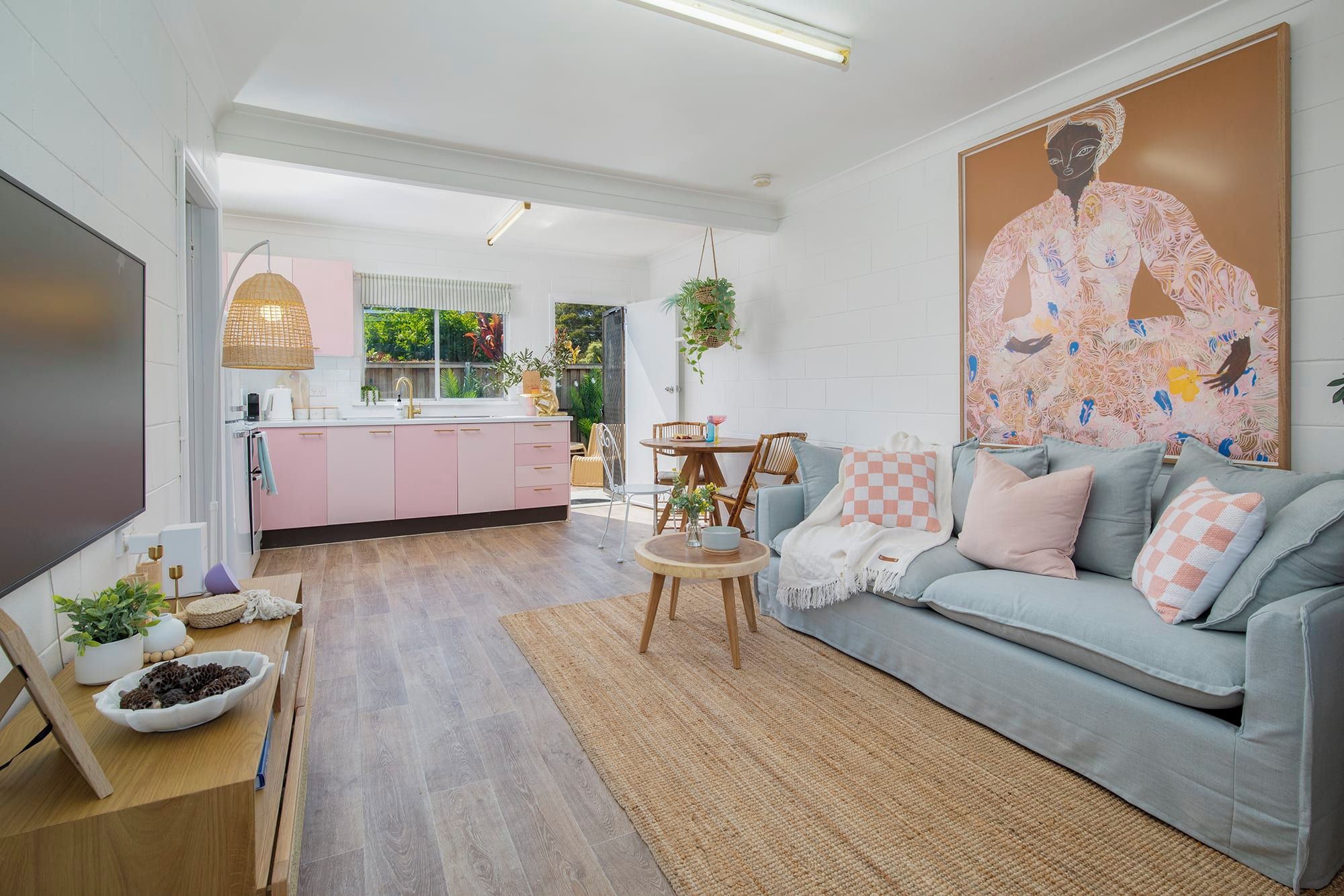 Una sala de estar moderna con un sofá gris, una mesa de centro y una cocina al fondo.