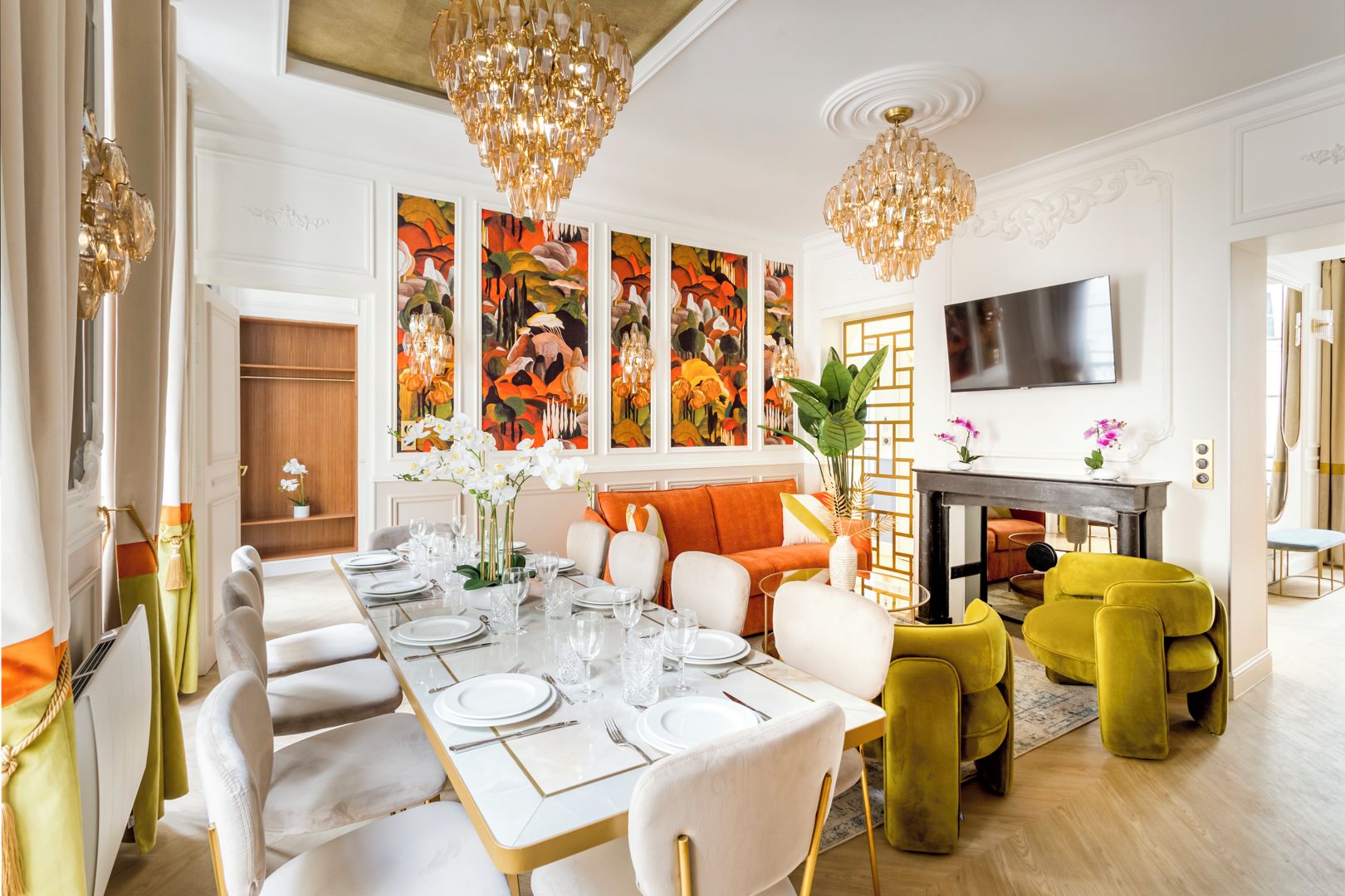 A dining area with a long table set for a meal, a sofa, and a television.
