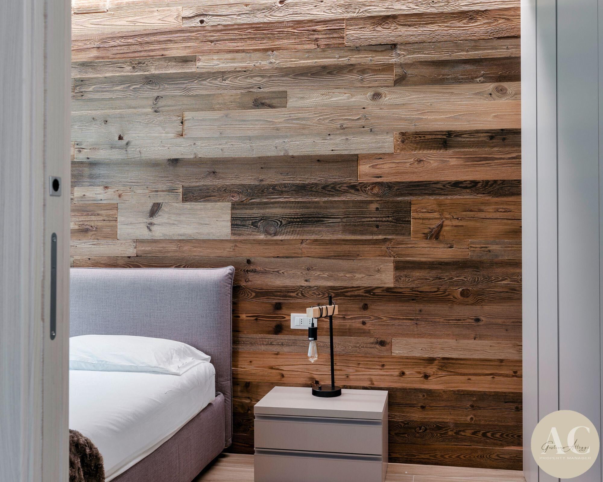 Un dormitorio con cama, mesita de noche y lámpara.