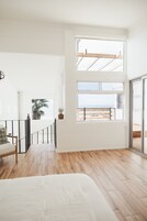 A spacious room with a large window offering a view of the beach and palm trees.