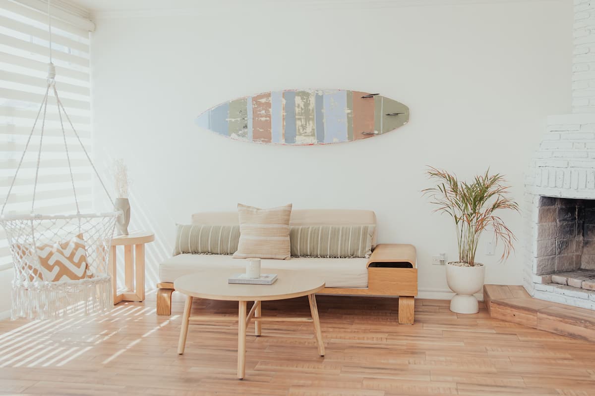 A living room with a sofa, a coffee table, a hanging chair, and a fireplace.