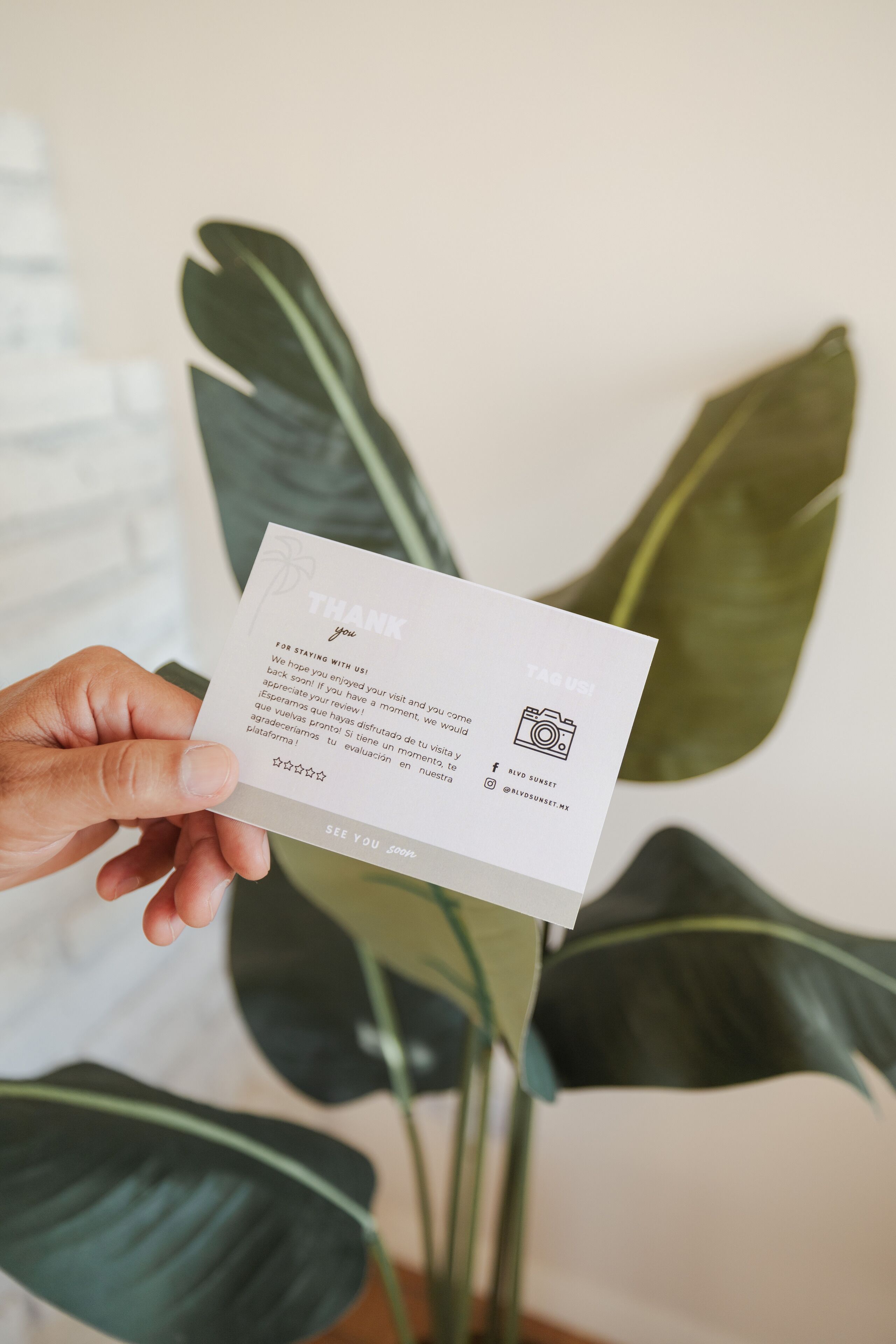 Una mano sosteniendo una tarjeta de presentación con texto y un código QR.