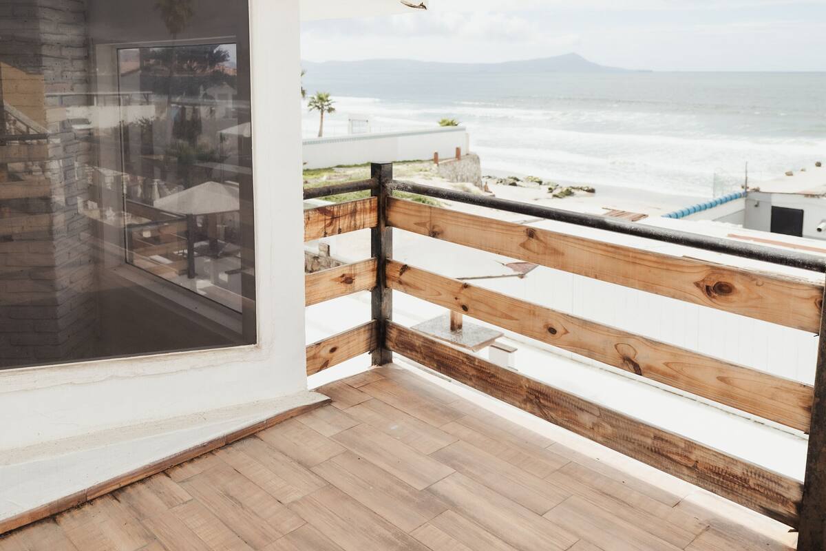 A wooden deck with a view of the ocean and mountains.