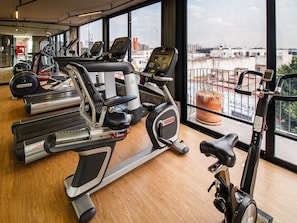 A gym with cardio machines, a weight bench, and a large window with a city view. - Comfortable Loft w/Terrace, Gym & Coworking | 2 BD | Tribu Colon (Guadalajara)