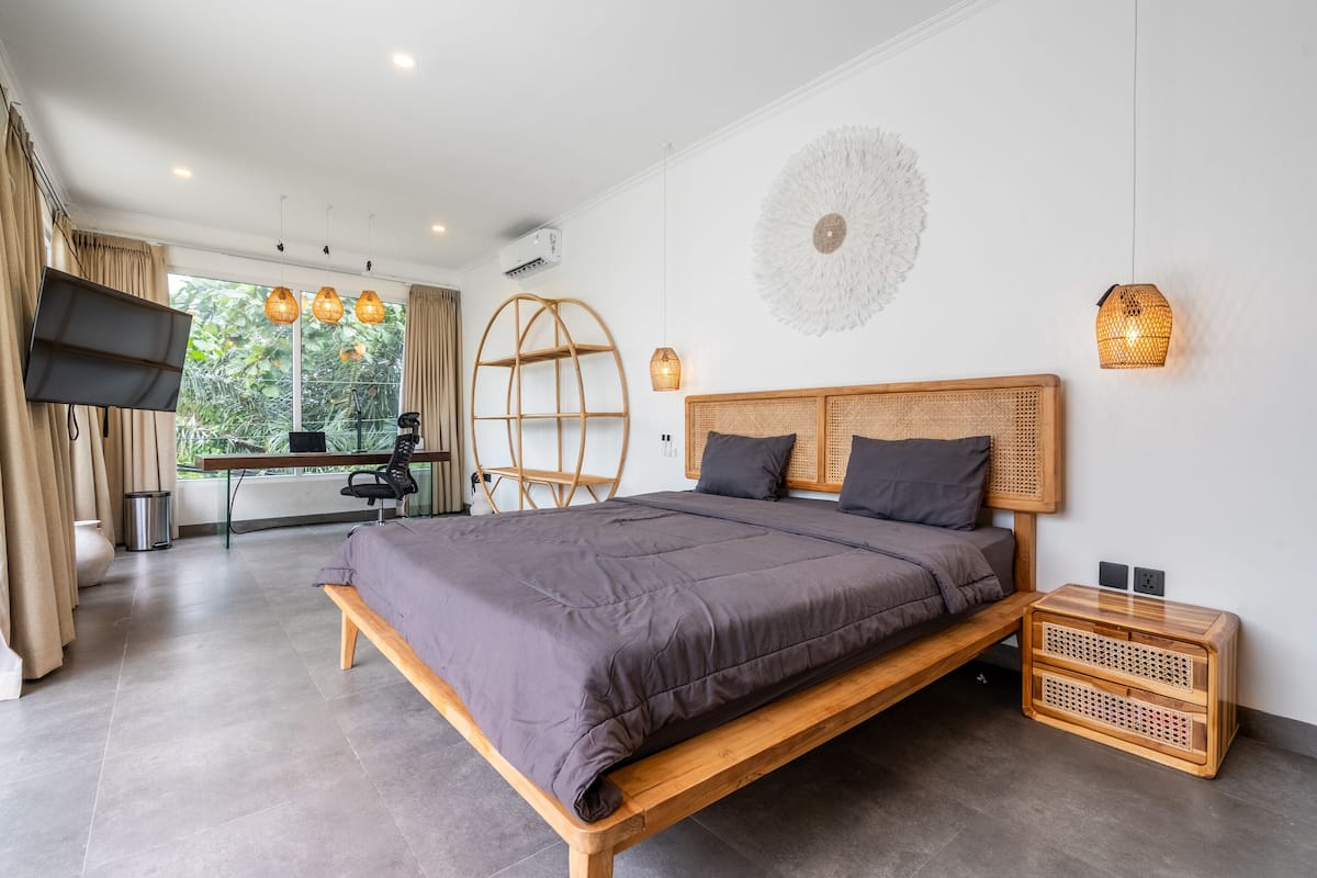 A modern bedroom with a wooden bed, a desk, and a large window.