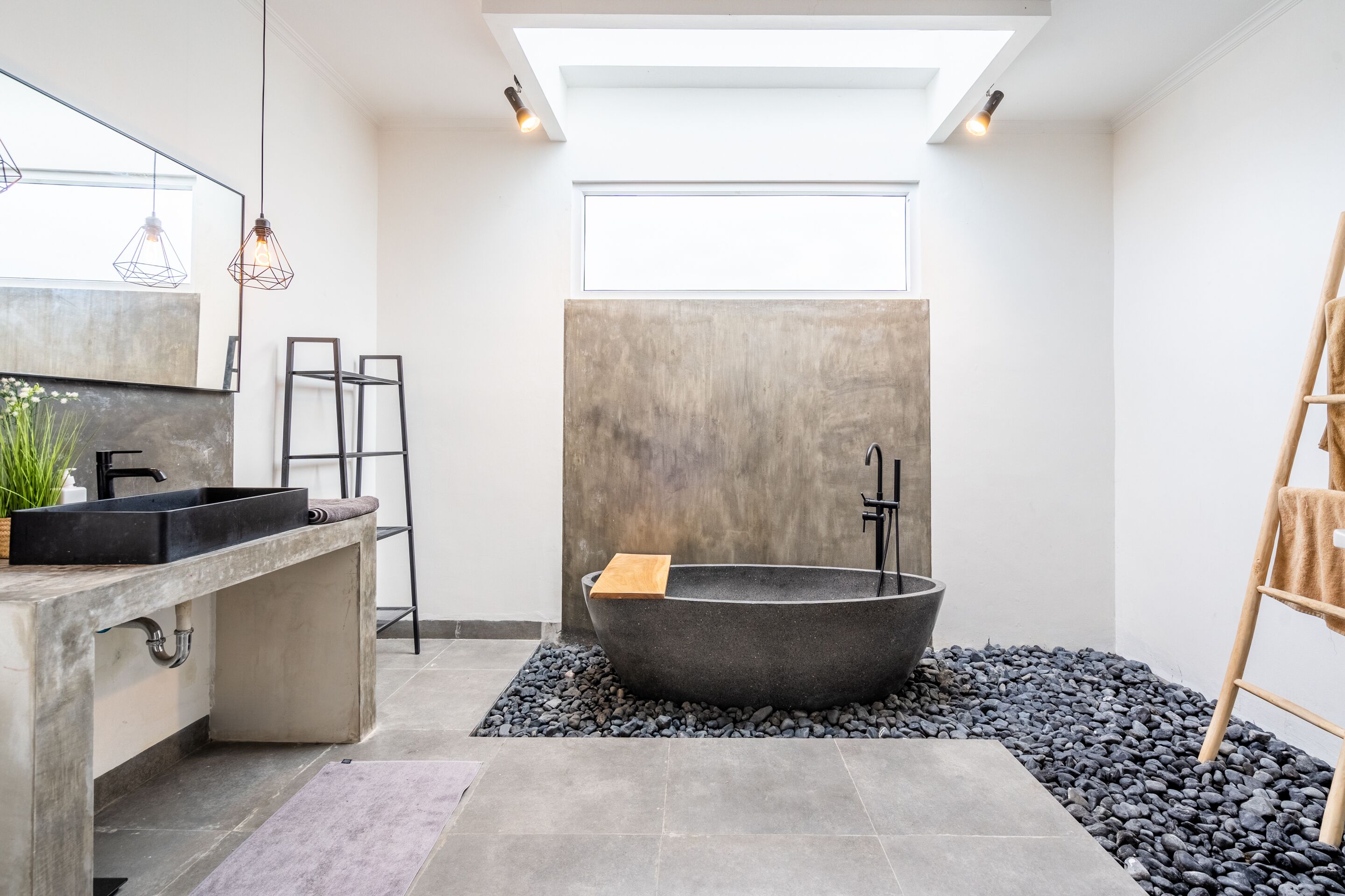 Un baño moderno con una bañera independiente, un espejo grande y un tragaluz.
