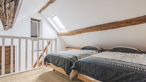 Ein Schlafzimmer mit zwei Betten, einer schrägen Decke, einem Oberlicht und einer Holztreppe.