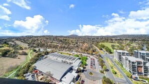 A large stadium with a parking lot, surrounded by residential areas and hills. - Chic 1-Bed with Stunning Lake View & Indoor Pool (Belconnen)