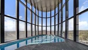 An indoor swimming pool with a panoramic view through large windows. - Chic 1-Bed with Stunning Lake View & Indoor Pool (Belconnen)