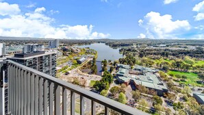 A high-rise building with a view of a lake and surrounding greenery. - Chic 1-Bed with Stunning Lake View & Indoor Pool (Belconnen)