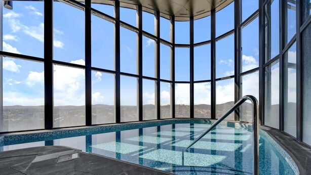 A modern indoor pool with a clear view of the surrounding landscape through large windows. - Chic 1-Bed with Stunning Lake View & Indoor Pool (Belconnen)