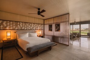 Een moderne hotelkamer met een groot bed, bedlampen, een plafondventilator en uitzicht op de omgeving.