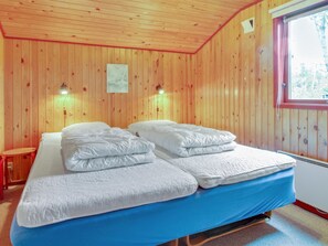 Un dormitorio con paneles de madera, una cama, dos lámparas de noche y una ventana.