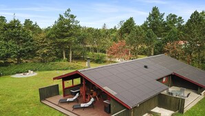 Een modern terras buiten met een overdekte zithoek en een barbecue.