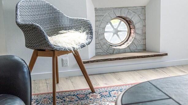A modern room with a woven chair, a round window, and a patterned rug. - "Arnora" - 48km from the sea by Interhome (Højer)