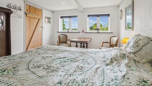 A bedroom with a bed, two windows, a wooden door, a small table, and a chair. - "Arnora" - 48km from the sea by Interhome (Højer)