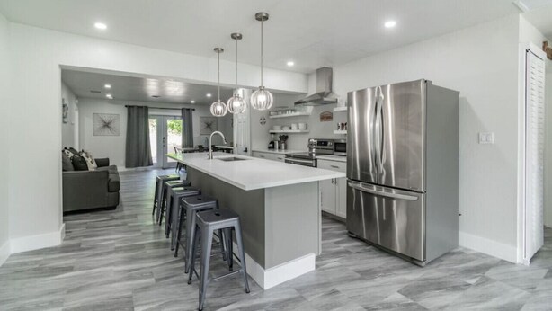 A modern kitchen with a central island, stainless steel appliances, and pendant lighting.