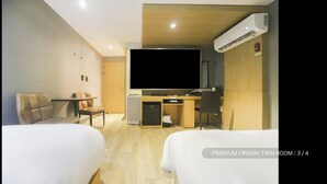 Una habitación con dos camas, un escritorio, un televisor y aire acondicionado.