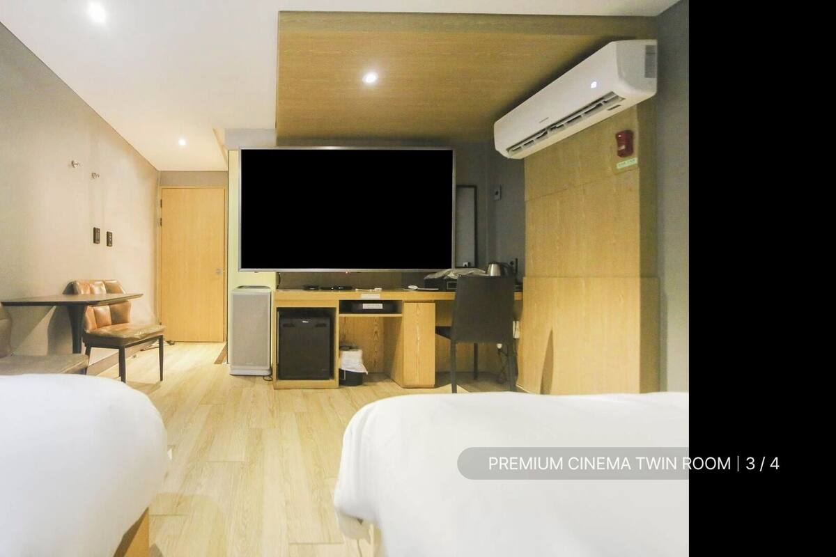 Ein Zimmer mit zwei Betten, einem Schreibtisch, einem Fernseher und einer Klimaanlage.