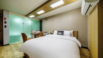 A hotel room with a large bed, a desk with a chair, a green wall, and a wooden ceiling.
