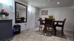 A dining area with a wooden table and chairs, a large mirror, and a ceiling light fixture. - Spacious, Pet Friendly Basement Apartment  (Milton)
