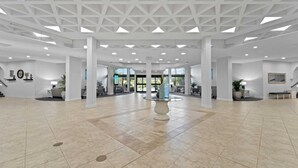 Een ruime lobby met een hoge plafond, grote ramen en een centrale decoratietafel.