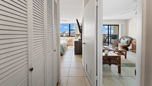 Een gang die leidt naar een slaapkamer met een bed, een dressoir en een stoel.