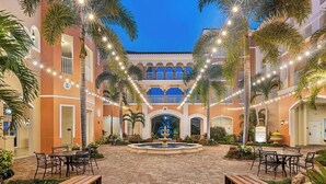 Un patio con una fuente, mobiliario exterior e iluminación con luces colgantes.