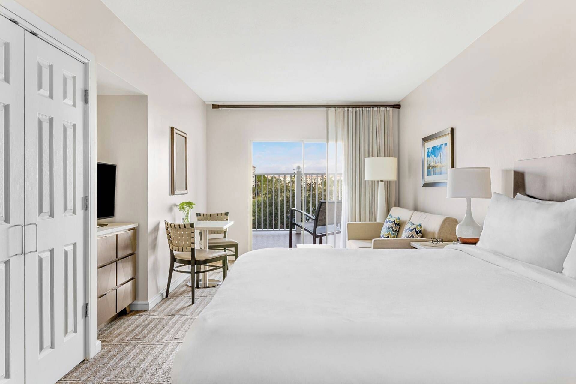 Une chambre d’hôtel avec un grand lit, un bureau avec une chaise, une télévision et un balcon avec vue.